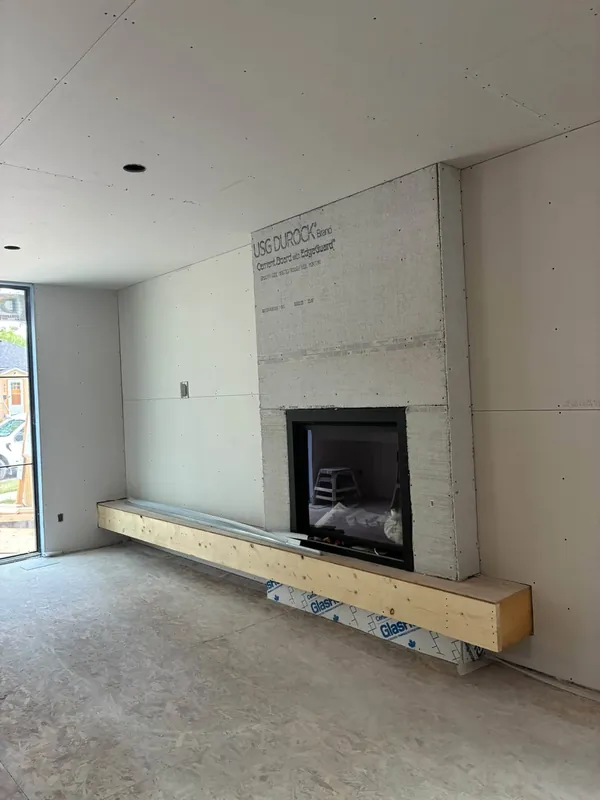 A fireplace wall sheathed in USG Durock cement board with a timber hearth built out below, the surrounding drywall hung