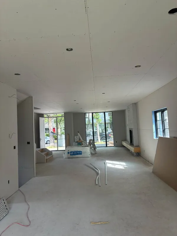 A large interior with every wall and ceiling sheet hung and screwed, the joints still open and ready for taping