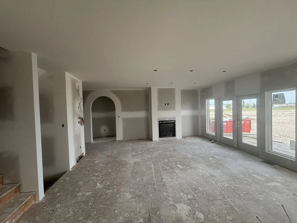 A newly boarded interior in Lethbridge with an arched doorway and a fireplace set into the wall, sliding doors opening onto the site